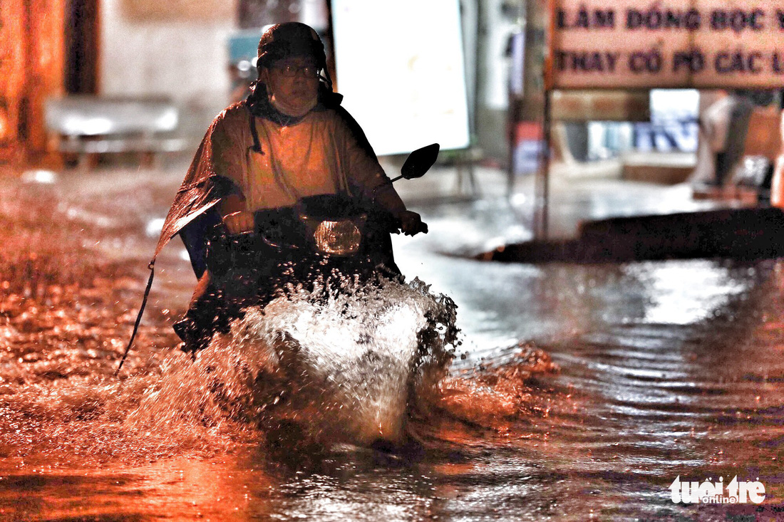 A man travels on an inundated road in Binh Tan District.