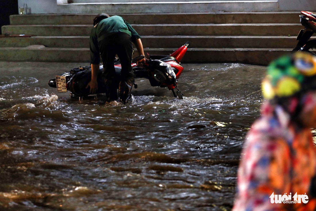 A man picks up his motorbike amid the floodwater.