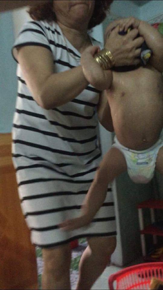 A woman at a daycare center in Da Nang lifts a child by grabbing his head in this photo uploaded to social media.