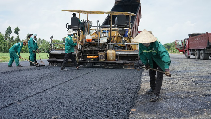 Workers add asphalt to the road leading to the bridge in Cao Lanh City, Dong Thap Province. Photo: Tuoi Tre