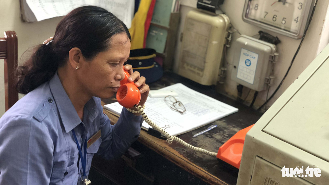 Nguyen Thi Nam listens to train information via telephone at her level crossing booth in Hanoi. Photo: Tuoi Tre