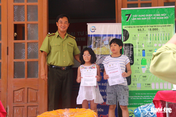 Two children are awarded certificates for their participation in the exhibition. Photo: Tuoi Tre