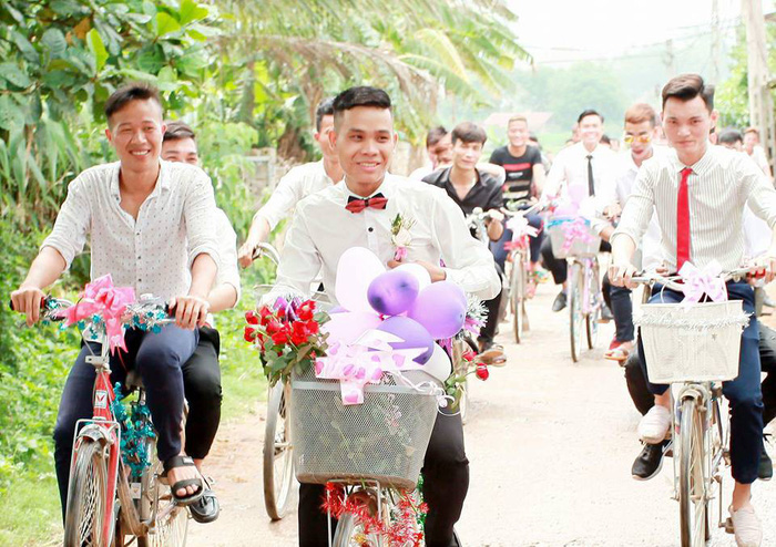 Le Van Truong (foreground) rides a bicycle to the bride’s house on his weeding day in Vinh Phuc, Vietnam, May 30, 2018, in this provided photo
