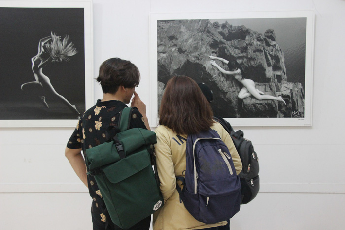 Three college students watch photos on display at