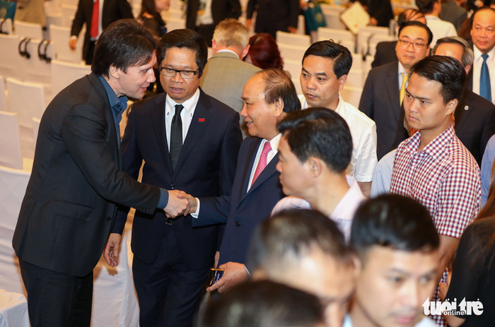 Vietnamese Prime Minister Nguyen Xuan Phuc (pink tie) shakes hands with a participant at a conference in Hanoi, on June 17, 2018. Photo: Tuoi Tre