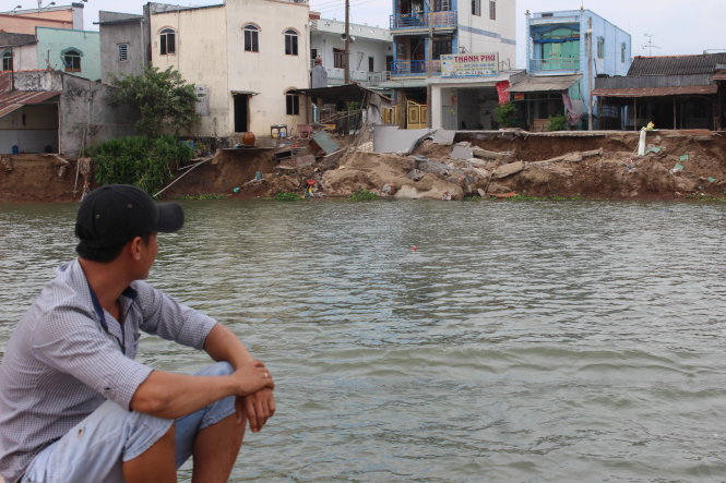 A man looks at an eroded road from a boat in An Giang Province, Vietnam. Photo: Tuoi Tre