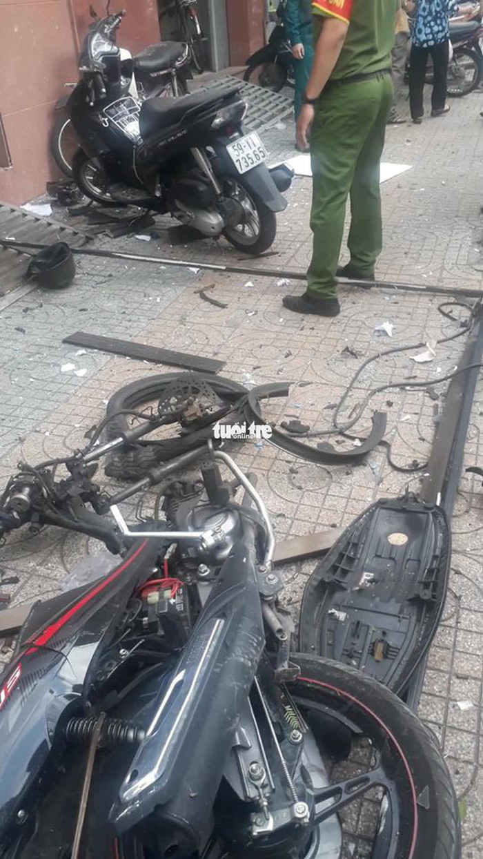 The heavily damaged motorbike lies on the sidewalk in front of the police headquarters. Photo: Tuoi Tre