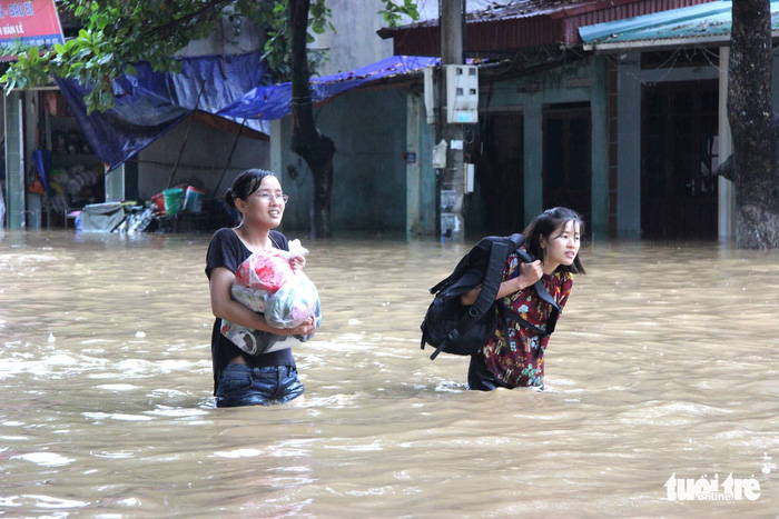 Two high school students walk among floodwater in Ha Giang.