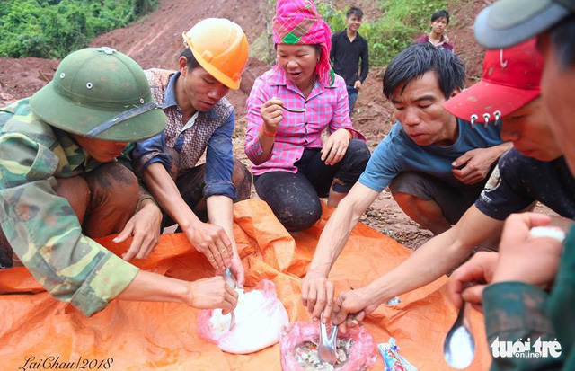 Residents and soldiers share a meal while taking a break from their search for the missing.