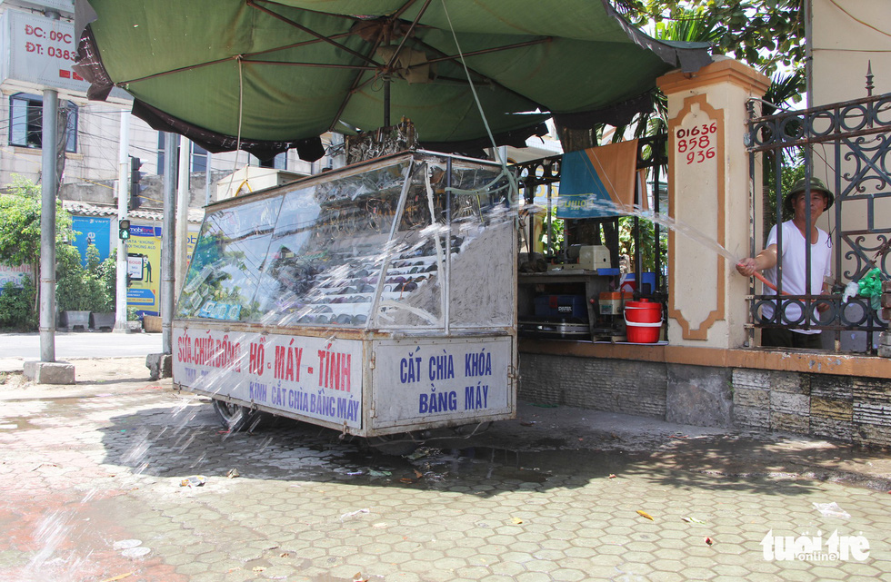 An owner of a key shop sprinkle water around his stall to cool off the atmosphere. .