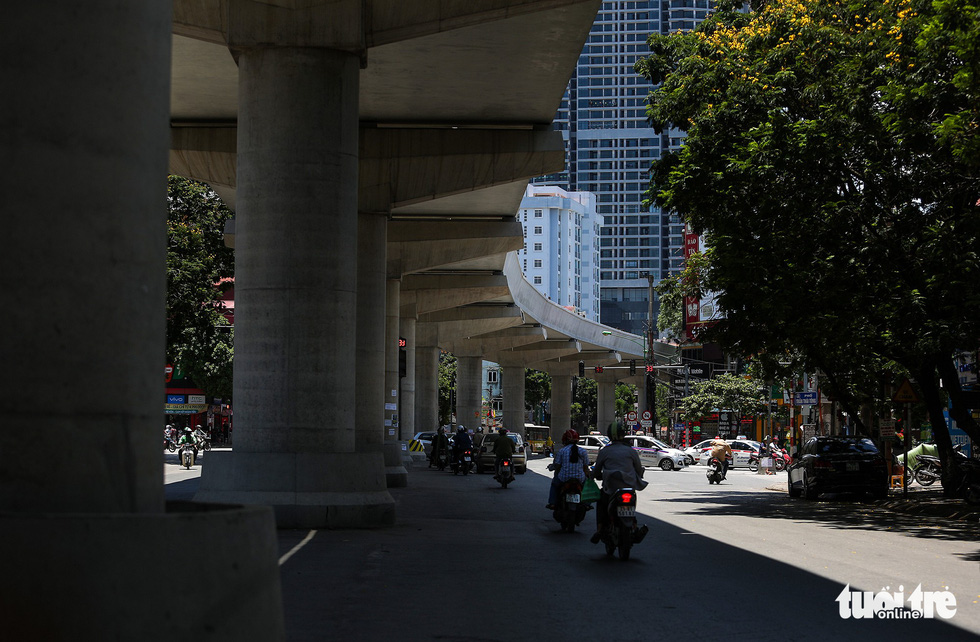 Commuters travel under the shade of an overpass.