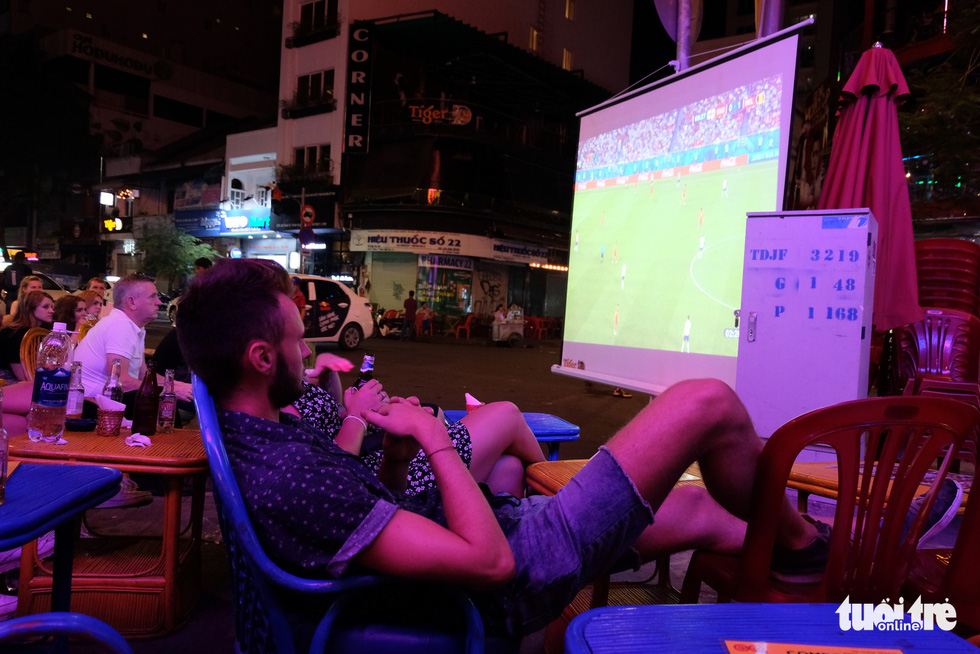 A man (foreground) sprawls in a chair while watching a 2018 FIFA World Cup game in Ho Chi Minh City, Vietnam, June 29, 2018. Photo: Tuoi Tre