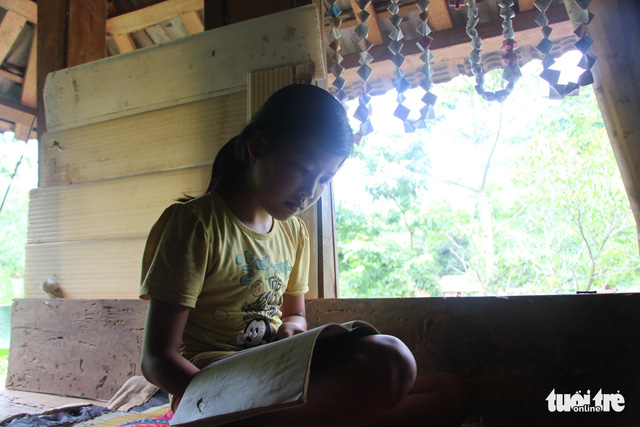 Khieu studies beside a window, taking advantage of the natural sunlight .