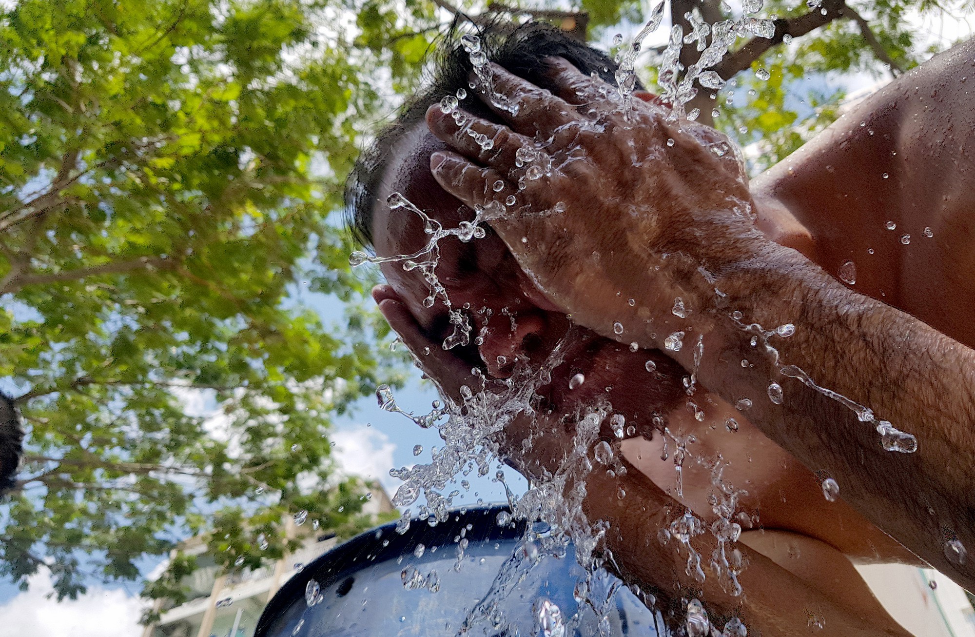 A drainage worker washes his face along a street in Ho Chi Minh City, Vietnam. Photo: Tuoi Tre