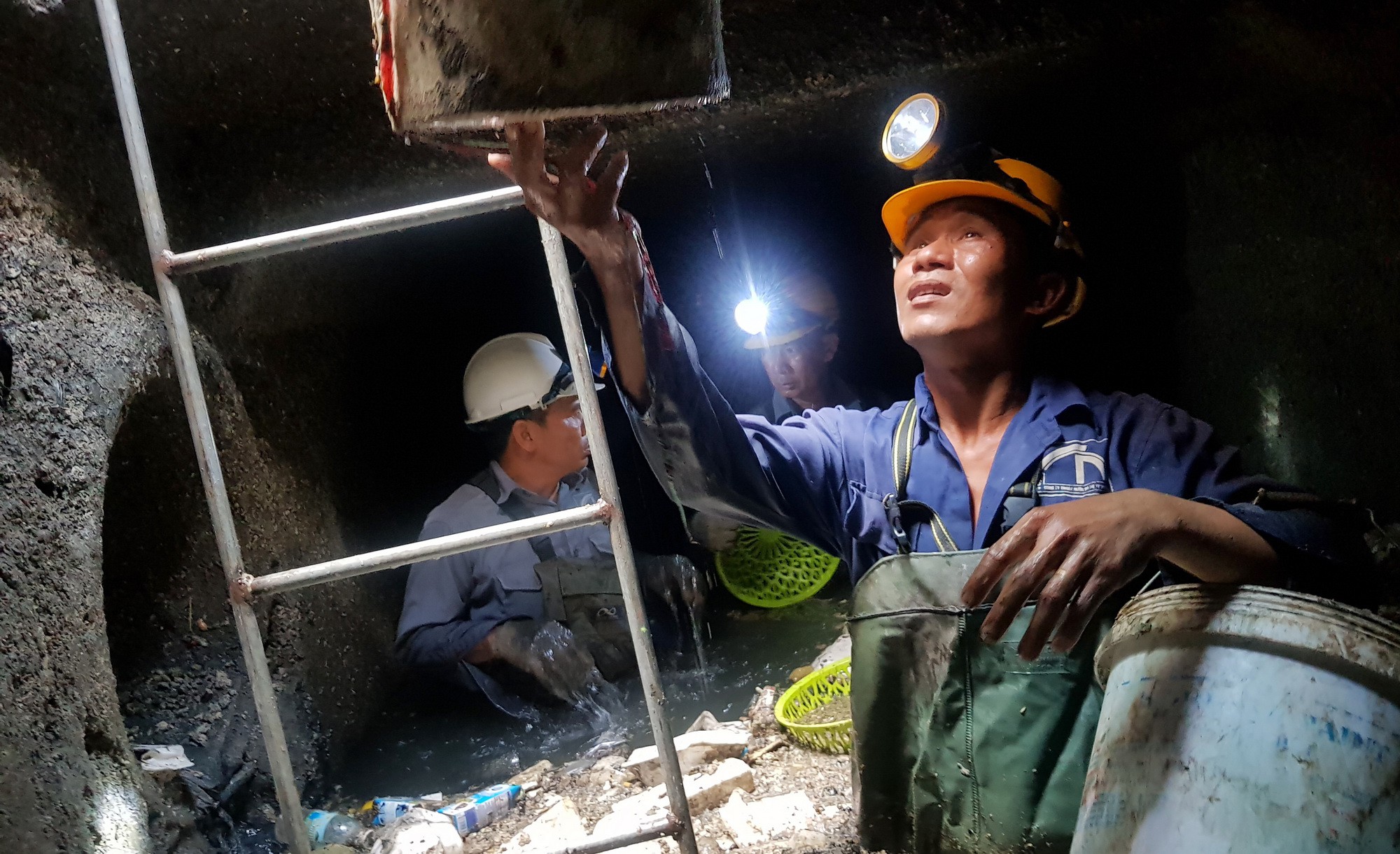 A drainage worker watches a garbage bucket being lifted from a sewage pipe in Ho Chi Minh City, Vietnam. Photo: Tuoi Tre