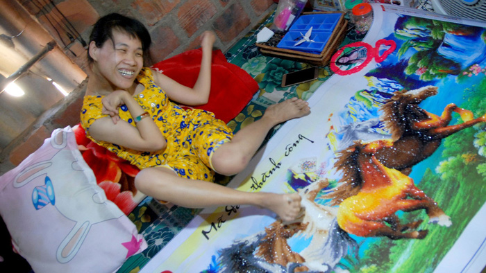 Vo Thi Le Hang sits near a diamond painting at her house in Quang Binh Province, Vietnam. Photo: Tuoi Tre