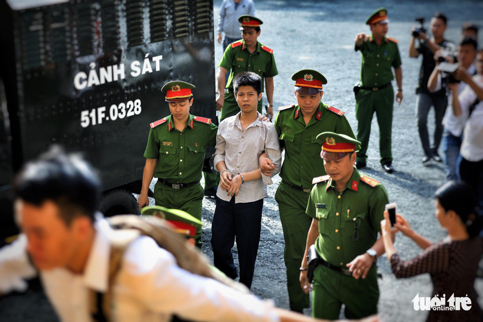 Nguyen Huu Tinh is escorted by police officers to a court in Ho Chi Minh City on July 9, 2018. Photo: Tuoi Tre
