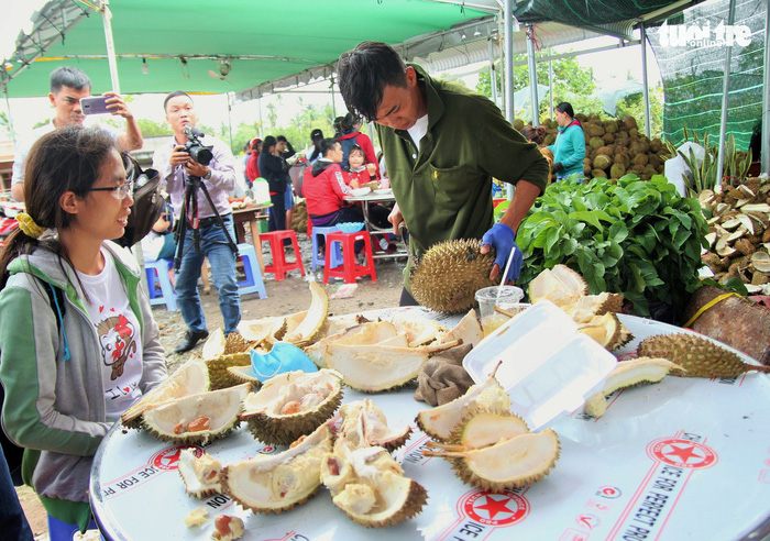 One of Ngan’s staff opens a durian for a customer. Photo: Tuoi Tre