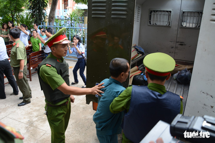 A defendant is escorted out of the courtyard. Photo: Tuoi Tre