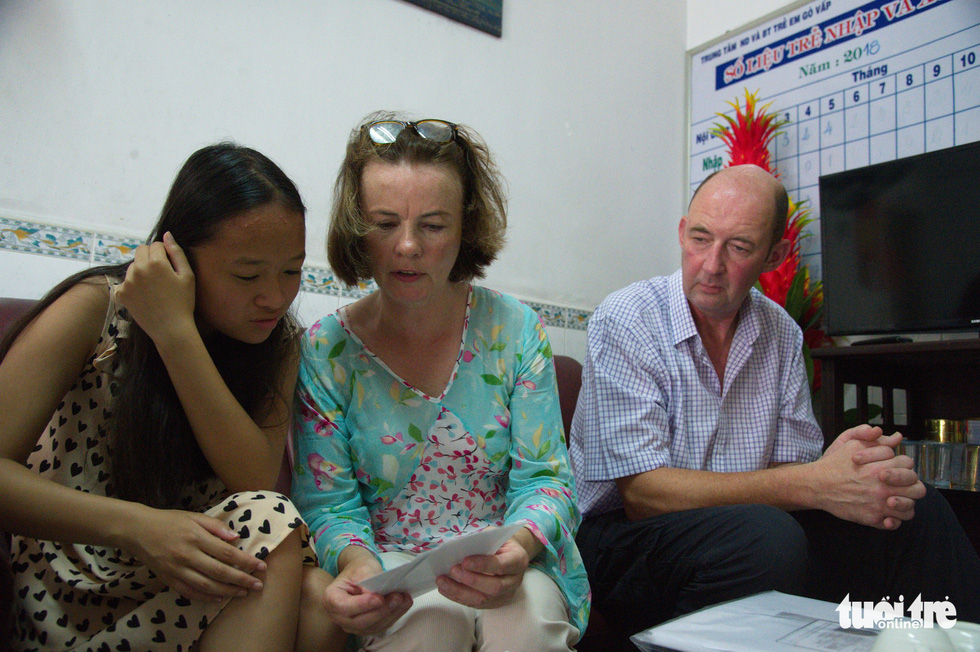 Suzanne Doran (C) shows her adoptive daughter photos taken of her as a kid during their visit to the Child Welfare and Protection Center of Go Vap District in Ho Chi Minh City. Photo: Tuoi Tre