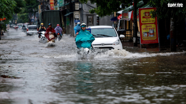 People travel on flooded Luong The Vinh Street in Hanoi on July 21, 2018. Photo: Tuoi Tre