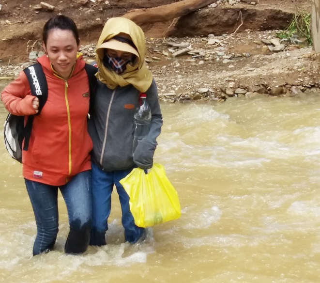 Two teachers cross a stream to get to their school in the north-central province of Nghe An. Photo: Tuoi Tre