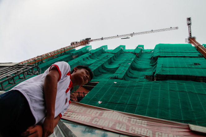 A man walks under a construction crane  in Hanoi without safety precautions. Photo: Tuoi Tre