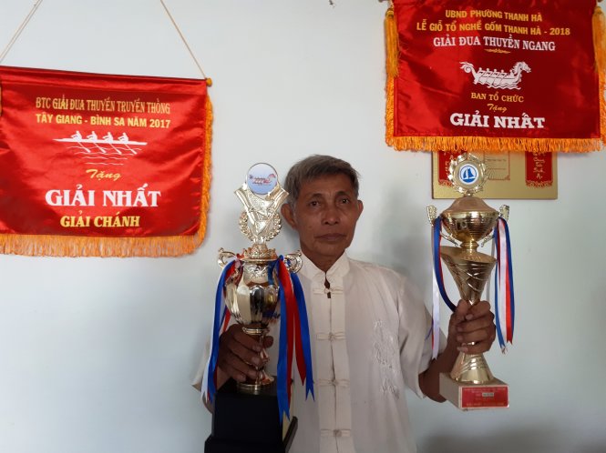 Pham Nhut holds trophies given by winning boat racing participants. Photo: Tuoi Tre