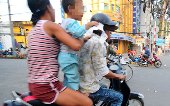 A duo and a child beggar in Ho Chi Minh City take off on a motorbike after noticing they were being photographed. Photo: Tuoi Tre
