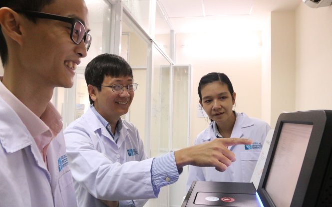 Dr. Giang Hoa (C) and demonstrates the functions of a piece of equipment at the Medical Genetics Institute in Ho Chi Minh City. Photo: Tuoi Tre