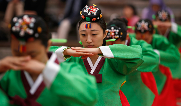 Women wearing the traditional Korean Hanbok costume perform deep bows during a traditional coming-of-age day ceremony at Namsangol Hanok Village in Seoul May 20, 2013.