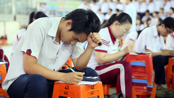 A grade 12 student is seen strenuously looking at his test paper in the same schoolyard.