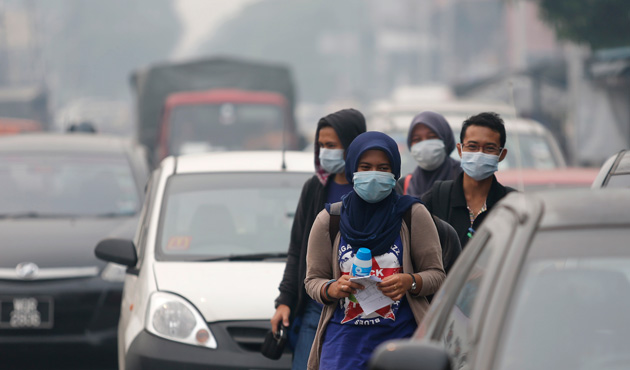 Pedestrians wear face masks as they walk along a hazy street in Kuala Lumpur June 23, 2013.