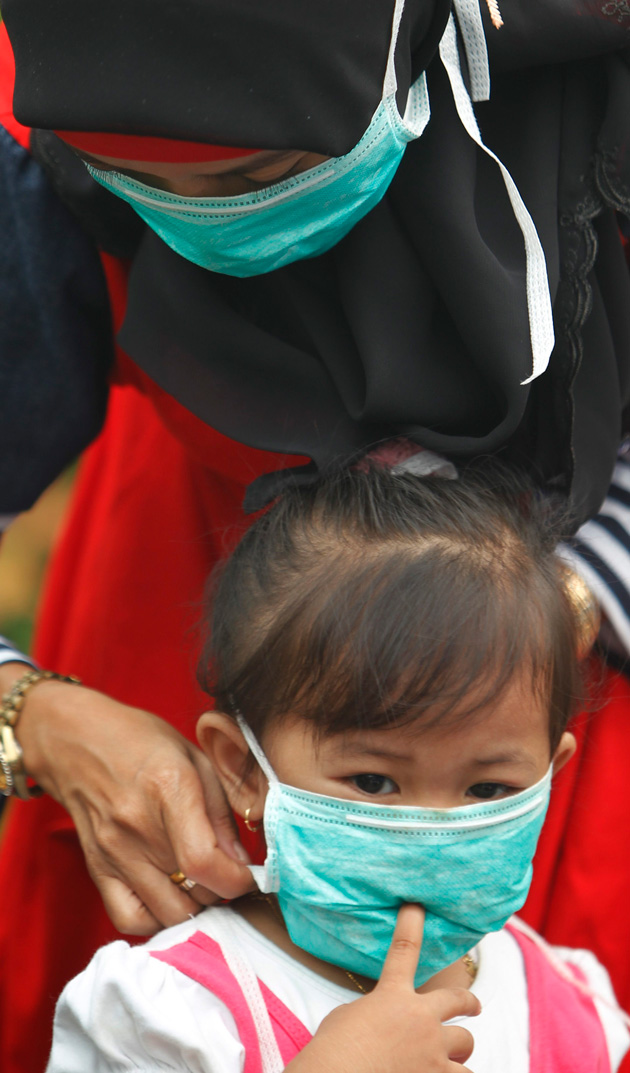 A mother fixes a mask for her child at a school at the haze hit Dumai, in Indonesia's Riau province June 22, 2013.