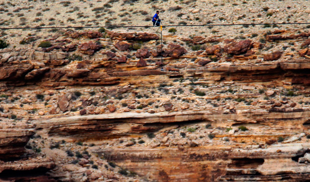 Daredevil Nik Wallenda pauses as he walks on a two-inch (5-cm) diameter steel cable rigged 1,400 feet (426.7 metres) across more than a quarter-mile deep remote section of the Grand Canyon near Little Colorado River, Arizona June 23, 2013.