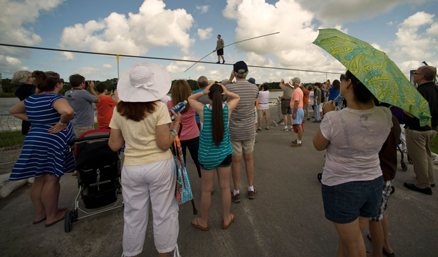 Fans watch as high wire walker Nik Wallenda (C) balances on a 1,200 foot-long (366 meter) cable during a practice session in Sarasota, Florida, June 14, 2013.