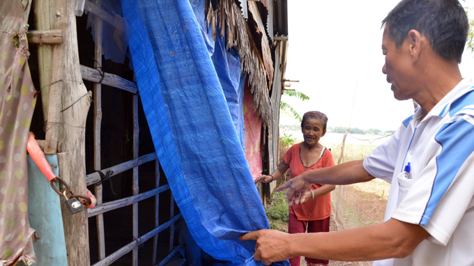 Dinh Van Lot, a farmer, surveys the dilapidated house of Nguyen Thi Theu in Tan Quoi commune as part of a plan to build her a new home.