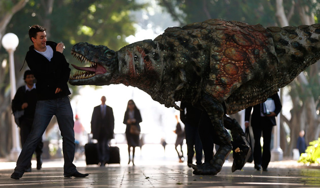 A man reacts as a performer dressed in a Tyrannosaurus rex dinosaur costume walks next to him during a publicity event in central Sydney August 28, 2013.