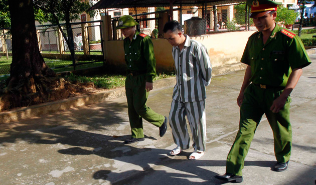 Police escort a man who is being released from Hoang Tien prison, about 100 km (62 miles) outside Hanoi August 30, 2013.