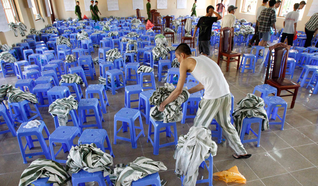 A man leaves his prison uniform on a stool amongst other discarded prison uniforms during his release from Hoang Tien prison, about 100 km (62 miles) outside Hanoi August 30, 2013.