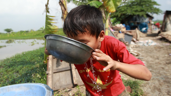 Ngo Doan Duc hurriedly gulps water to get to school on time.