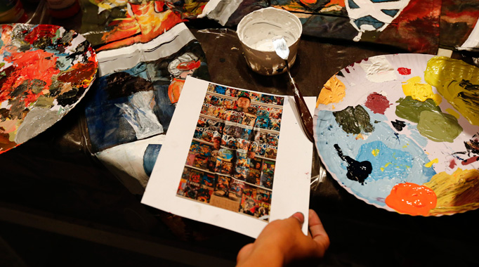 A picture of Chinese artist Liu Bolin standing partially blended into the background, a shelf lined with comic books, as part of a series of performances, is seen on a table in Caracas, November 1, 2013.