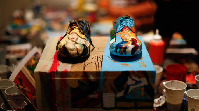 The shoes of Liu Bolin, a Chinese artist, are pictured before he wears them to blend himself into a backdrop, a shelf lined with comic books, as part of a series of performances in Caracas, November 1, 2013.