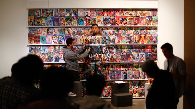 Liu Bolin, a Chinese artist, waits for the finishing touches to his camouflage, before being completely blended into the background, in front of a shelf lined with comic books, as part of a series of performances in Caracas, November 2, 2013.