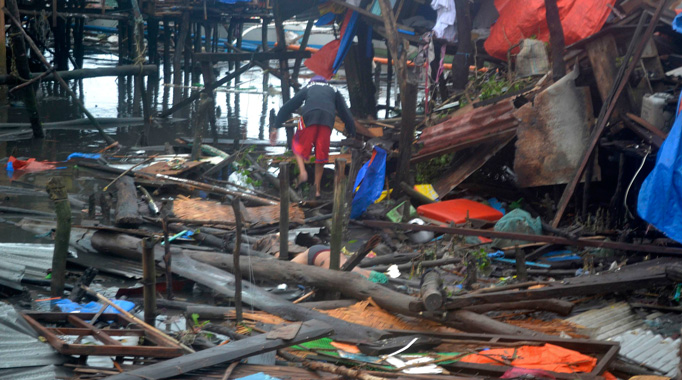 The body of a man lies among the debris as another tries to walk towards damaged houses after Typhoon Haiyan hit the municipality of Coron, Palawan province in central Philippines November 9, 2013.