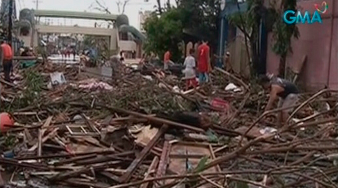 People walk on a flooded street filled with debris after Typhoon Haiyan hit the central Philippine city of Tacloban, Leyte province in this still image from video November 8, 2013.