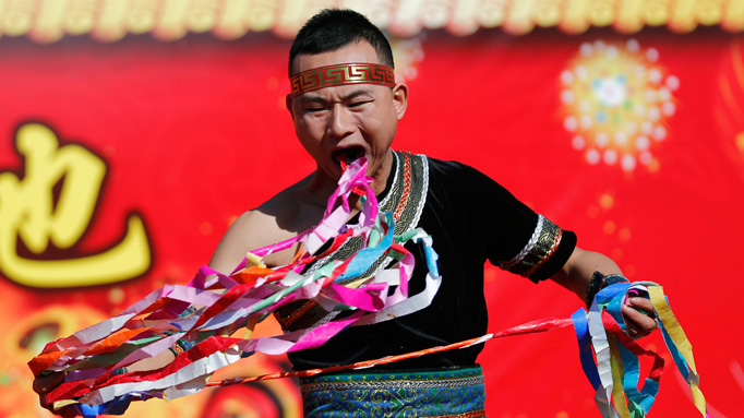A man pulls ribbons from his mouth as he performs a feat of his strength during the opening of the temple fair for Chinese New Year celebrations at Ditan Park, also known as the Temple of Earth, in Beijing January 30, 2014.