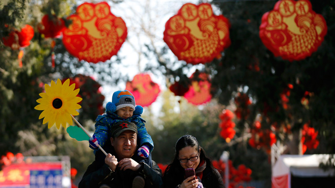 A family walks underneath Chinese New Year decorations during the opening of the temple fair for the Chinese New Year celebrations at Ditan Park, also known as the Temple of Earth, in Beijing January 30, 2014.