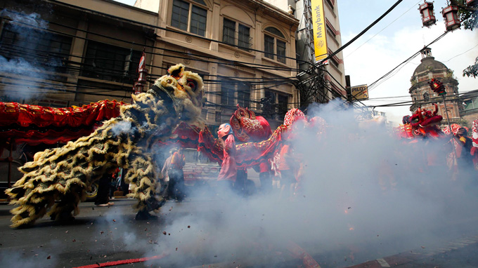 Filipino-Chinese residents perform the dragon and lion dance as firecrackers explode during the eve of the Chinese New Year in Manila's Chinatown January 30, 2014.