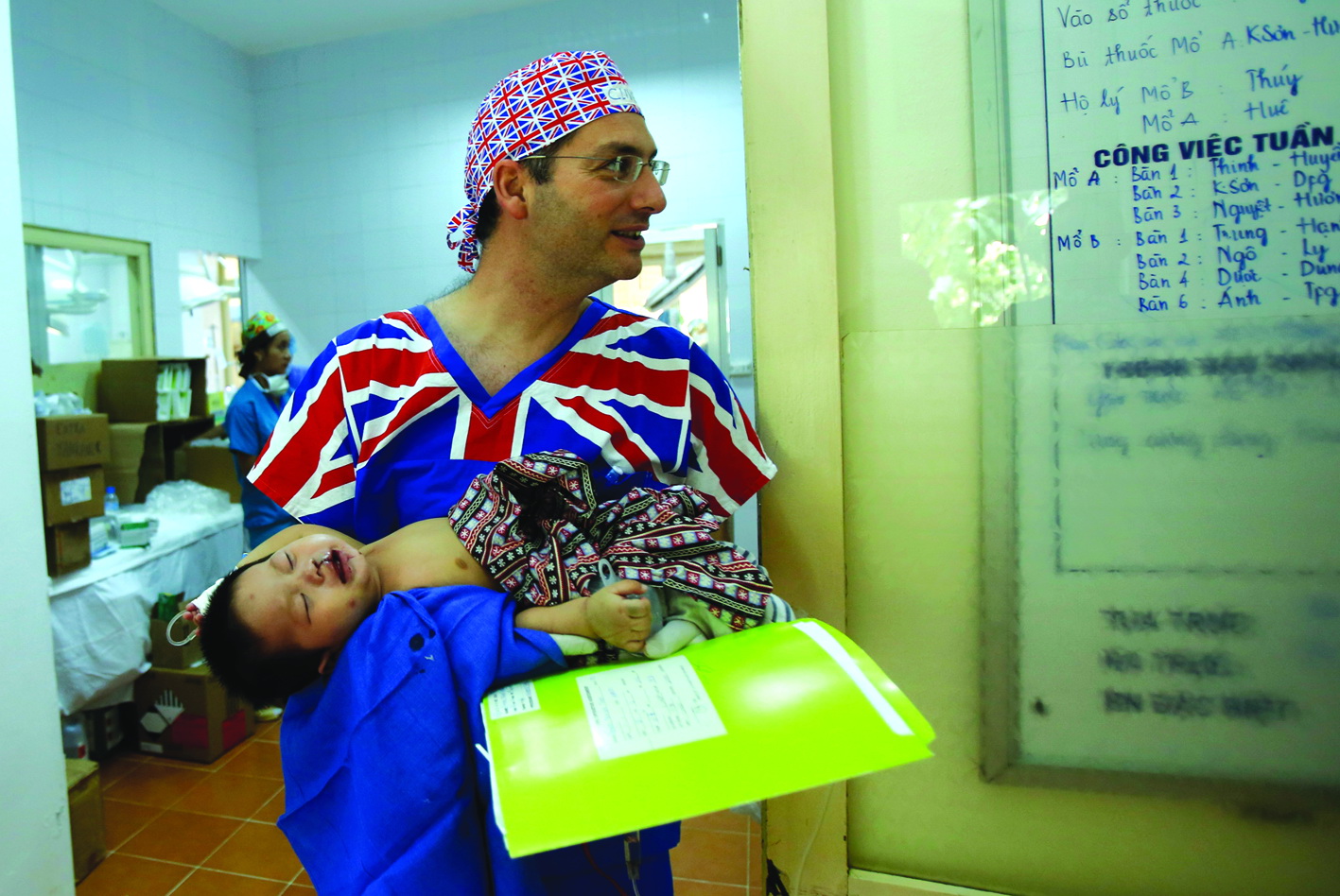 Doctor Clive, from the U.K., is seen taking a kid to the recovery room after a successful operation.